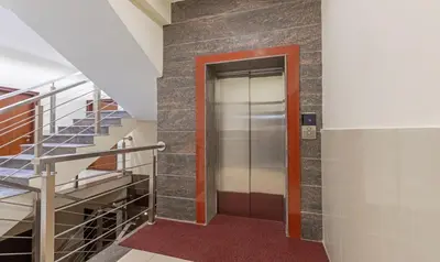 a hallway with a staircase and a glass elevator at Treebo Samanvaya Retreat, Mysore in Mysore