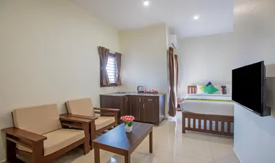 a hotel room with a bed and a couch and chair at Treebo Samanvaya Retreat, Mysore in Mysore