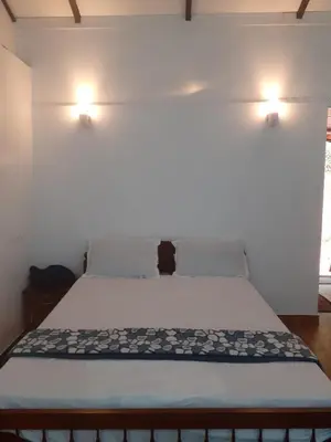 a bed with a black cat sitting on top of it at River View Guest Rooms in Vythiri