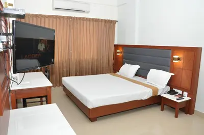 a bedroom with a large bed and a flat screen tv at Hotel Royal Chambers in Coimbatore