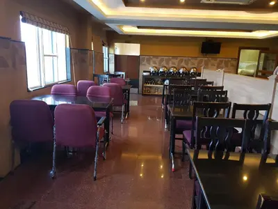 a dining room with purple chairs and tables in a restaurant at Hotel Royal Chambers in Coimbatore