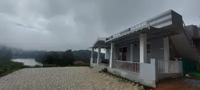 a building with a balcony with a view of a river at Sky High Villa - Premium Cottages in Ooty