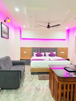 a bedroom with a bed and a couch and pink lights at Marhaba plaza in Kozhikode