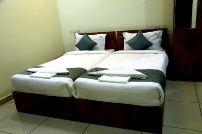 a large bed with white and green pillows on it at Homey Residency vythiri in Padinjarathara