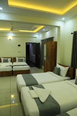 a hotel room with three beds in a room at Homey Residency vythiri in Padinjarathara