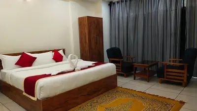 a bedroom with a bed with red pillows and chairs at Homey Residency vythiri in Padinjarathara