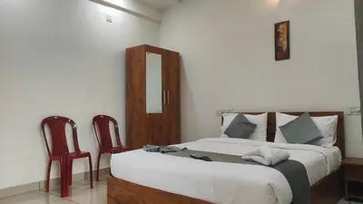 a bedroom with a large bed and two chairs at Homey Residency vythiri in Padinjarathara