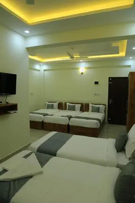 a hotel room with four beds and a tv at Homey Residency vythiri in Padinjarathara