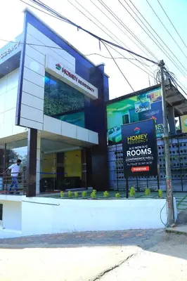 a large building with a sign in front of it at Homey Residency vythiri in Padinjarathara