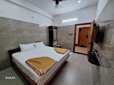 a bedroom with a bed and a television in it at Viruksham Residency in Palani