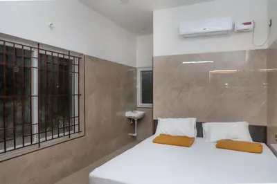 a bedroom with a white bed and a window at Viruksham Residency in Palani
