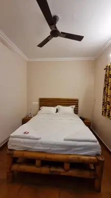 a bedroom with a bed with a ceiling fan at The Alpine Inn in Gūdalūr