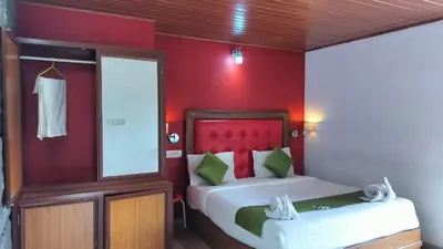 a bedroom with a bed with a red wall at Achus Holidays in Munnar