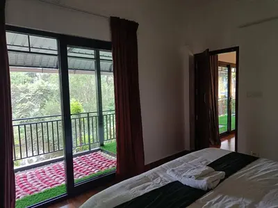 a bedroom with a bed and a view of a balcony at Cozy 3 BHK PoolVilla near Nagerhole National park. in Wayanad