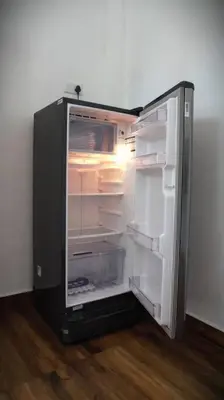 an empty refrigerator with its door open in a room at Cozy 3 BHK PoolVilla near Nagerhole National park. in Wayanad