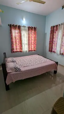 a bedroom with a bed in a room with windows at Delight Homestays Coorg in Kushālnagar