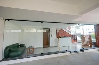 a glass room with a green couch in a room at HOTEL VARDHA Inn in Bhavāni