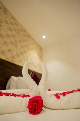a white swan decoration on a bed with a rose at HOTEL VARDHA Inn in Bhavāni