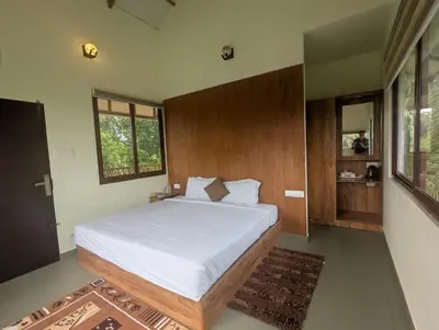 a bedroom with a large bed with white sheets at Neelambari Ecotoursm in Trichūr