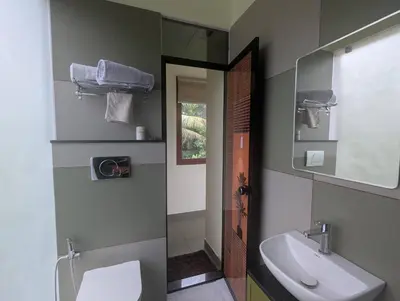 a bathroom with a sink and a toilet and a mirror at Neelambari Ecotoursm in Trichūr