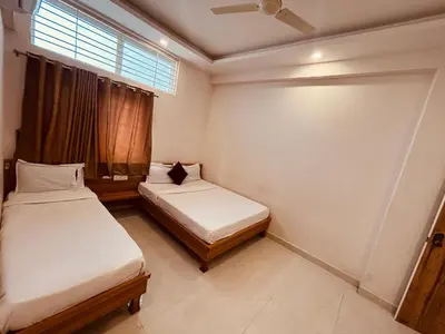 two beds in a small room with a window at Seema Palace Inn 1 km from Railwaystaion in Mysore