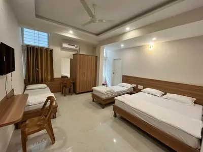 a bedroom with two beds and a desk and a television at Seema Palace Inn 1 km from Railwaystaion in Mysore