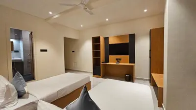 a living room with a bed and a television at Emerald Urban Comforts in Mysore