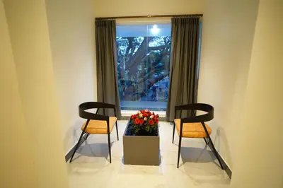two chairs and a box of flowers in a room with a window at Emerald Urban Comforts in Mysore