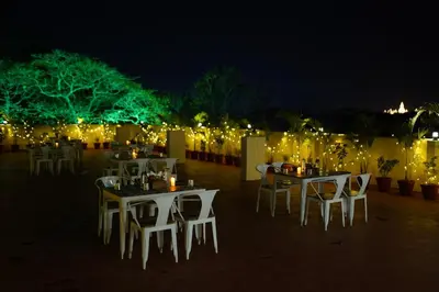 a group of tables and chairs with lights at night at Emerald Urban Comforts in Mysore