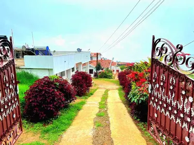 a dirt road with a gate and some bushes at VERMONT HOMe STAY in Ooty