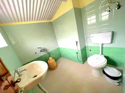 a green bathroom with a toilet and a sink at VERMONT HOMe STAY in Ooty