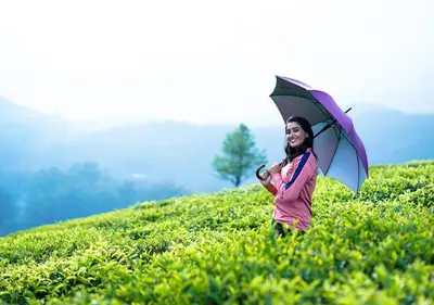 a woman holding an umbrella in a field at Viriparai Tea Bungalow Munnar by VOYE HOMES - Surrounded by Tea Plantations in Munnar