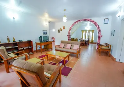 a living room with a couch and an archway at Viriparai Tea Bungalow Munnar by VOYE HOMES - Surrounded by Tea Plantations in Munnar