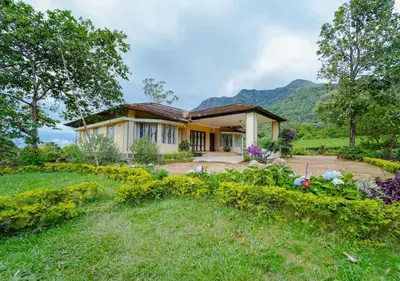 a house with a garden in front of it at Viriparai Tea Bungalow Munnar by VOYE HOMES - Surrounded by Tea Plantations in Munnar