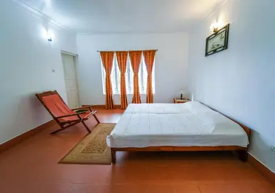 a bedroom with a bed and a chair in it at Viriparai Tea Bungalow Munnar by VOYE HOMES - Surrounded by Tea Plantations in Munnar