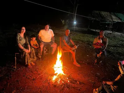 a group of people sitting around a fire at River view cottage in Vythiri