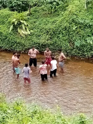a group of people standing in a river at River view cottage in Vythiri