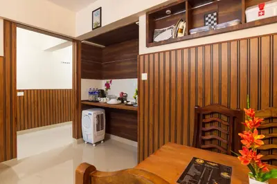 a room with wooden walls and a table and a kitchen at Sancta Maria Airport Hotel in Cochin