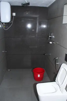a bathroom with a toilet and a red bucket at Airy Homestay Ooty by Lexstays in Ooty