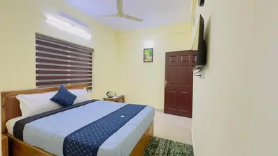 a bedroom with a bed with blue pillows and a window at Mystique Inn Wayanad-vythiri in Vythiri