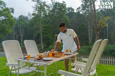 a man standing at a table with food on it at Stayvista at Mudra Manor 4BR - Coffee Estate Comp Breakfast Big Heated Pool in Madikeri