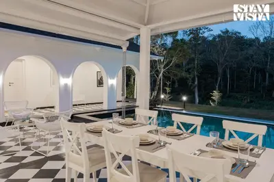 a dining room with a table and chairs on a checkered floor at Stayvista at Mudra Manor 4BR - Coffee Estate Comp Breakfast Big Heated Pool in Madikeri