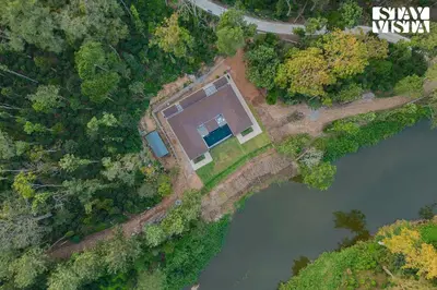 an aerial view of a house next to a river at Stayvista at Mudra Manor 4BR - Coffee Estate Comp Breakfast Big Heated Pool in Madikeri