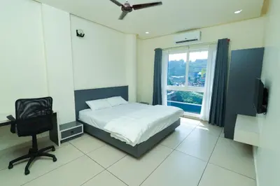 a bedroom with a bed and a desk and a window at RIVULET HOTEL APARTMENTS in Mukkam