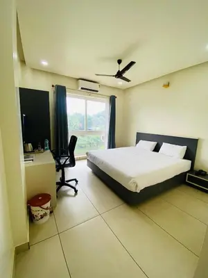 a bedroom with a bed and a desk and a window at RIVULET HOTEL APARTMENTS in Mukkam