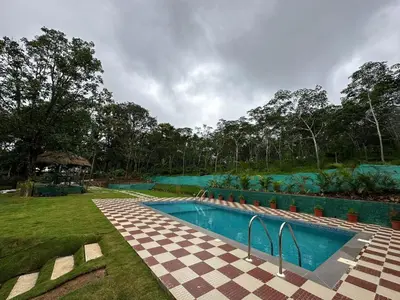 a swimming pool in a yard with a checkered sidx sidx sidx at The Mallika Holidays - A Cabin in Mananthavady