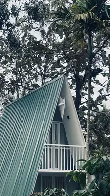 a house with a white roof and a tree at The Mallika Holidays - A Cabin in Mananthavady