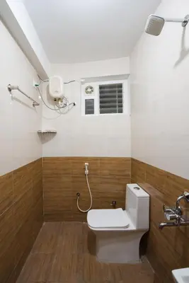 a bathroom with a toilet and a window at AAFIYA LAKEVIEW APARTMENTS in Coimbatore