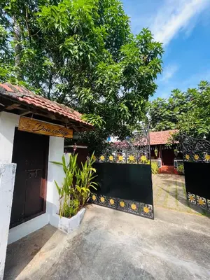 a house with a gate and a tree at Dove cottage in Cherai Beach
