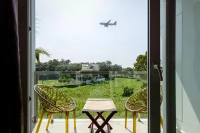 an open door to a balcony with two chairs and an airplane at ESAA Airport Hotel in Cochin